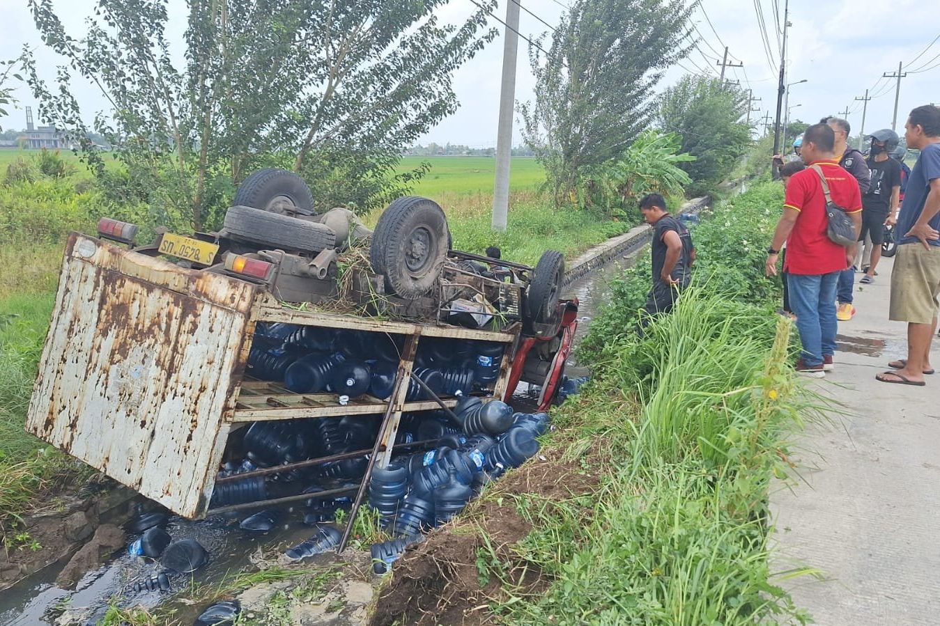 Hindari Pemotor, Truk Engkel Bermuatan Galon Terbalik ke Parit di Mojoanyar