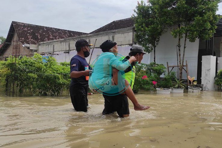 EVAKUASI: Salah seorang relawan saat mengevakuasi warga yang berada di usun Balong, Desa Banyulegi, Kecamatan Dawarblandong, Kabupaten Mojokerto dengan cara digendong, Kamis 10 Februari 2022. Fotografer: Karina Norhadini
