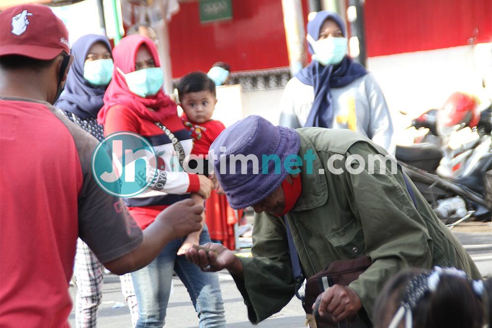 MEMBERI: Seorang pengunjung CFD memberi uang lelaki tua bertongkat di acara CFD, Minggu, 25 Oktober 2020. Fotografer: Hozaini
