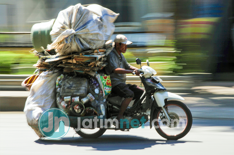 SEMANGAT: Di tengah pandemi Covid-19 yang memasuki bulan ramadan, seorang markenyot (pedagang barang rongsokan) tetap semangat mengais rejeki dengan mengangkut barang saat melintas di Jalan Kenanga, Kabupaten Situbondo. Fotografer: Hozaini