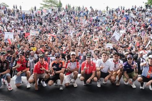 Para pembalap MotoGP peserta Riders Parade berfoto bersama di panggung Teras Udayana berlatar ribuan penonton, Rabu sore, 1 Oktober 2025. Dok: Mandalika Grand Prix Association (MGPA)