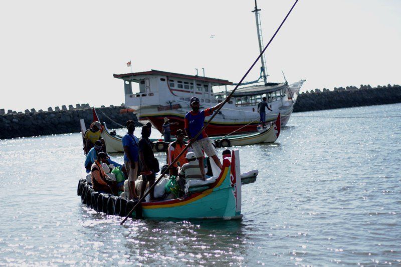 MENUJU DERMAGA. Perahu kecil (tambangan) membawa penumpang dari kapal perahu motor tradisional yang mengangkut penumpang dari Madura menuju dermaga Pelabuhan Kalbut, Tanjungpecinan, Mangaran, Situbondo, Sabtu, 12 Juni 2021. Foto: Hozaini